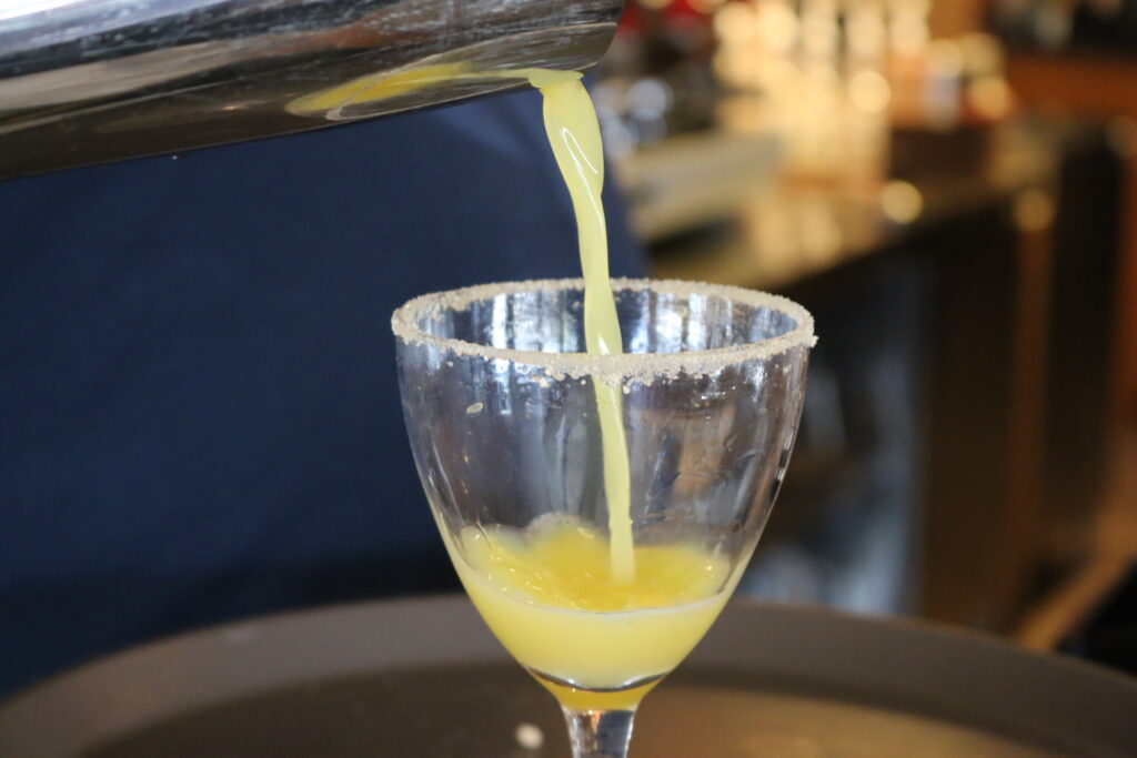 a breakfast margarita being poured into a maple sugar rimmed glass