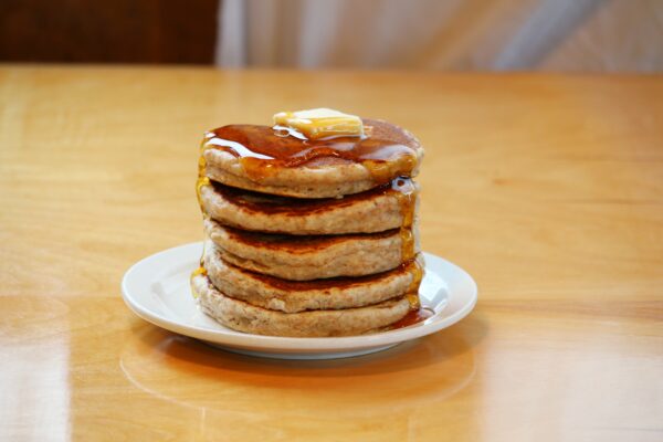 Oatmeal Pancakes made from Polly's Oatmeal Pancake Mix on a plate with maple syrup and butter
